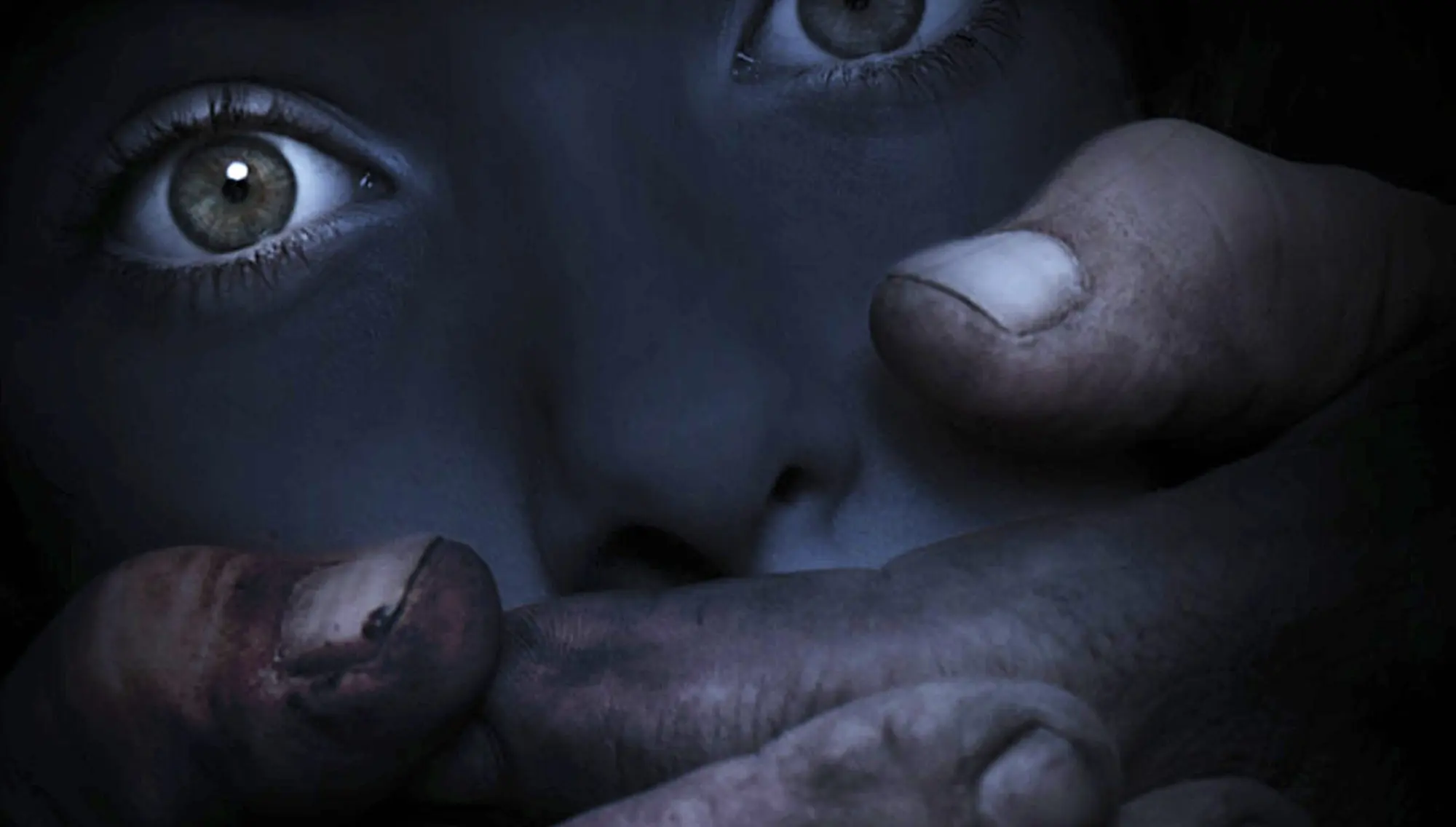 A frightened face in shadow, a hand pressed over the mouth